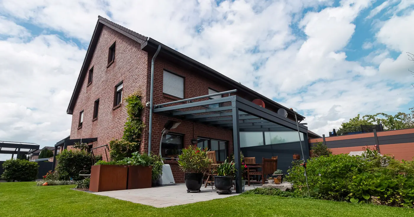 Terrassenüberdachung im Garten eines Klinkerhauses